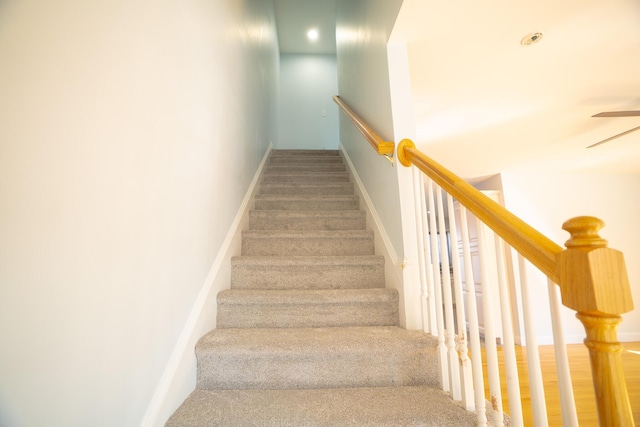 staircase with baseboards and a ceiling fan