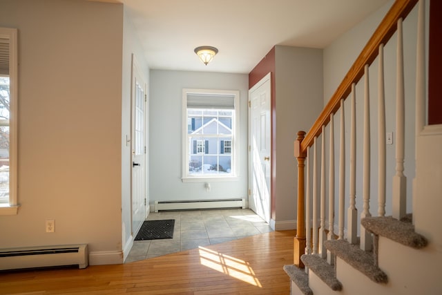 foyer with light tile patterned floors, a baseboard radiator, baseboards, and stairway