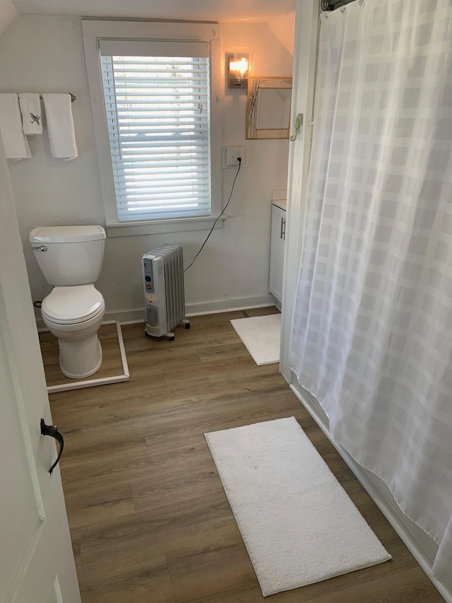 bathroom featuring a shower with curtain, toilet, wood finished floors, radiator heating unit, and baseboards