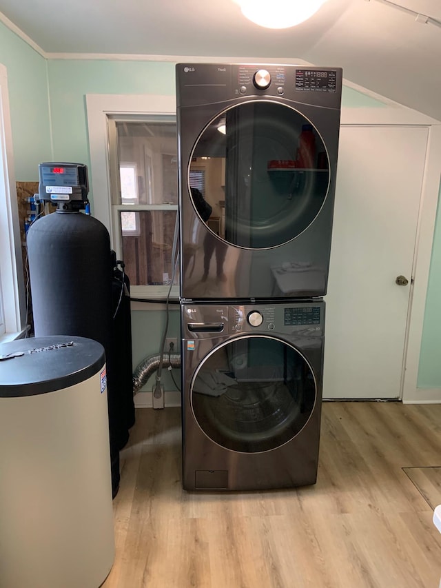 laundry room with laundry area, crown molding, wood finished floors, and stacked washing maching and dryer