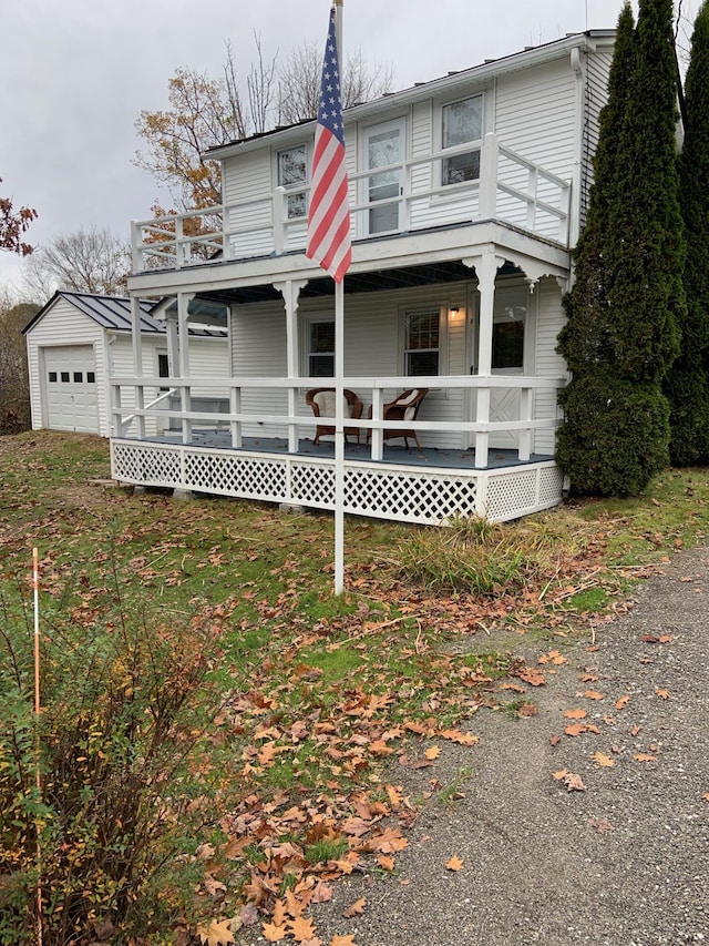 view of front of property with an outbuilding, a balcony, an attached garage, and covered porch