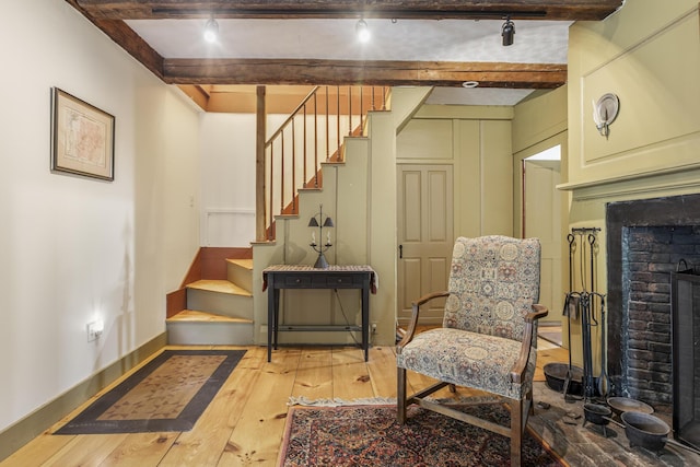 598 Walnut Hill Rd, North Yarmouth, ME 04097 - living area featuring stairs, light wood finished floors, beamed ceiling, a brick fireplace, and baseboards