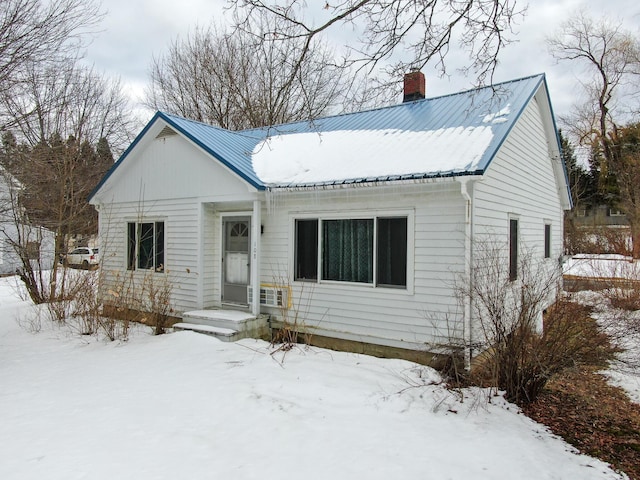 view of front facade featuring a chimney and metal roof