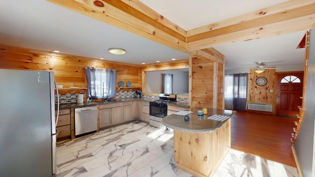 kitchen with plenty of natural light, marble finish floor, appliances with stainless steel finishes, and a peninsula