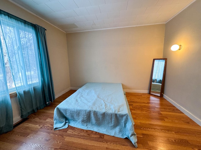 bedroom with multiple windows, wood finished floors, and crown molding