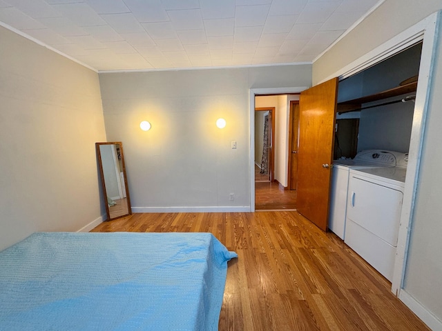 bedroom with light wood-style flooring, baseboards, ornamental molding, and separate washer and dryer