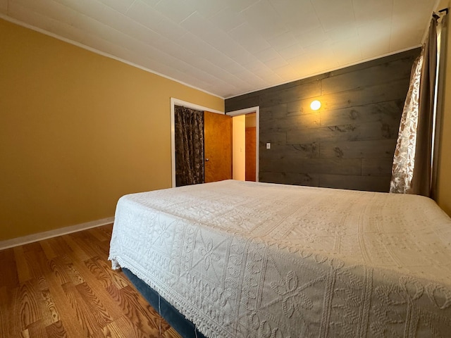 bedroom with wood walls, baseboards, and wood finished floors