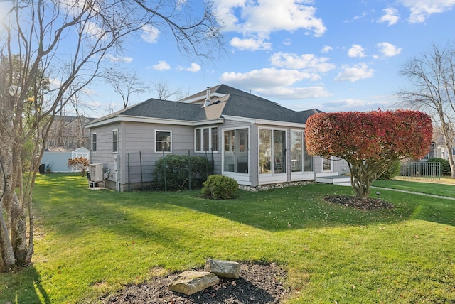 exterior space with a lawn, a shingled roof, fence, and a sunroom