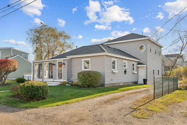 view of front of home featuring driveway, a shingled roof, a front yard, and fence