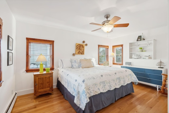 bedroom with light wood-type flooring, a baseboard heating unit, baseboards, and a ceiling fan