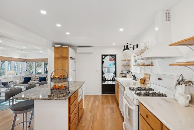 kitchen with a wall mounted AC, a sink, white appliances, light wood-style floors, and extractor fan