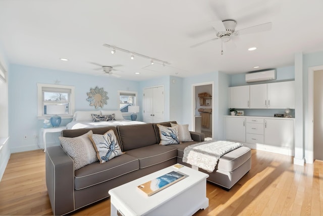 living room featuring a wall unit AC, recessed lighting, ceiling fan, rail lighting, and light wood-style floors