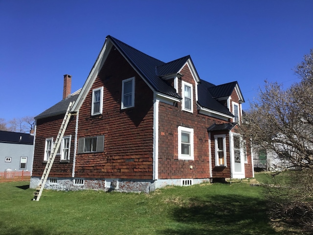 view of property exterior featuring a lawn, a chimney, and metal roof