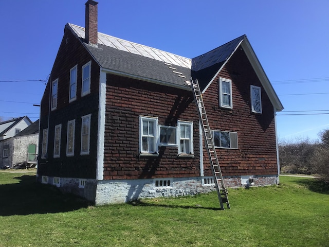 view of side of home with a lawn and a chimney