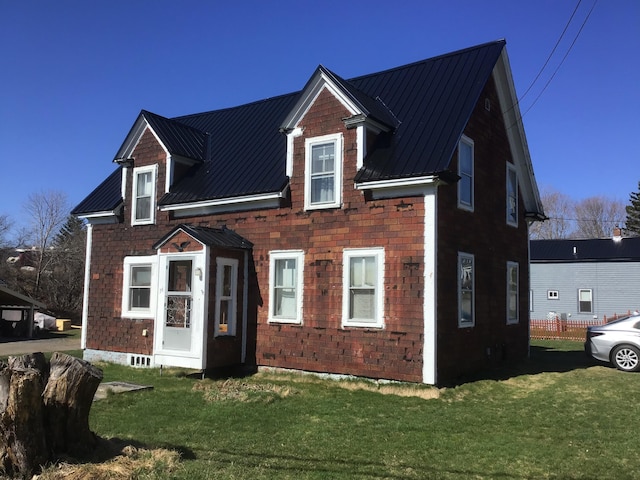 view of front of house featuring metal roof, a front yard, and a standing seam roof