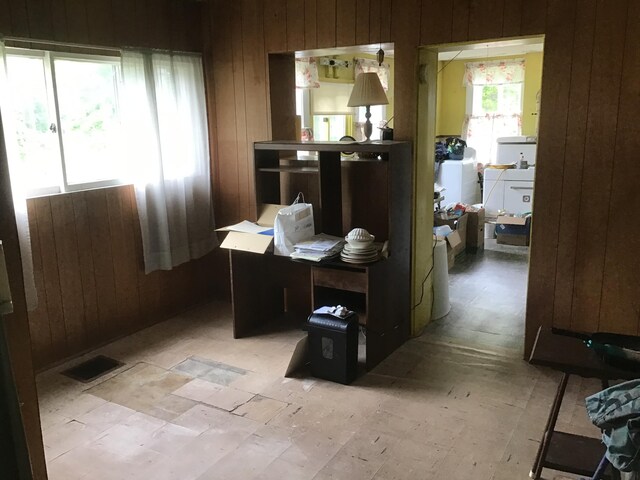 home office with visible vents, wood walls, and washing machine and dryer