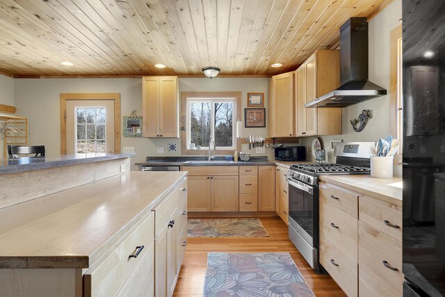 kitchen featuring light brown cabinetry, a healthy amount of sunlight, wall chimney exhaust hood, and black appliances