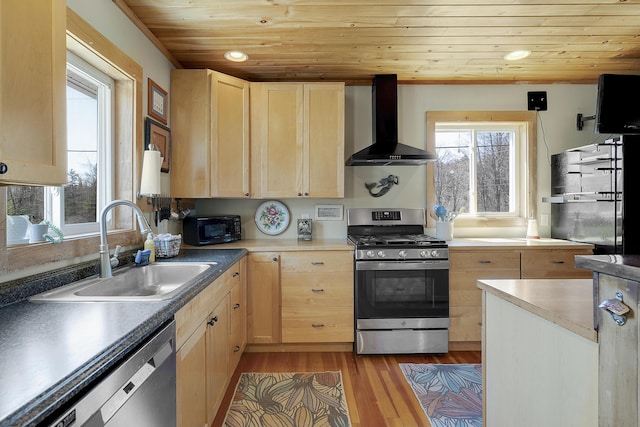 kitchen with wall chimney range hood, light brown cabinetry, a sink, stainless steel appliances, and wooden ceiling