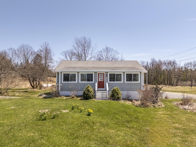view of front of home with entry steps, a shingled roof, and a front yard