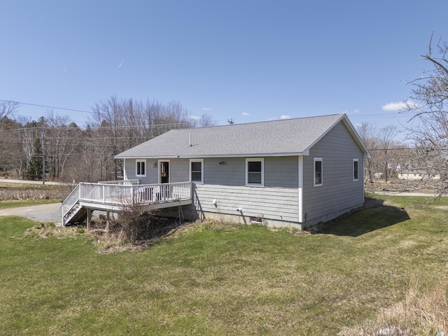 rear view of property with a yard, a deck, and roof with shingles