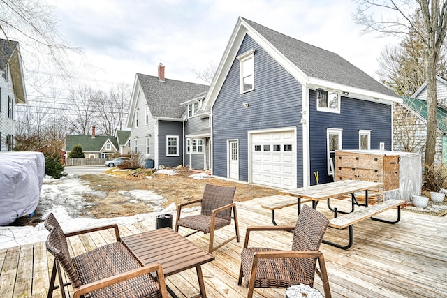 rear view of property featuring an attached garage, roof with shingles, and a wooden deck