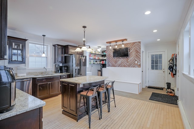 kitchen with dark brown cabinets, appliances with stainless steel finishes, crown molding, and a sink