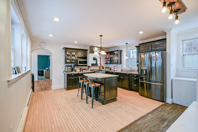 kitchen with refrigerator with ice dispenser, ornamental molding, a sink, stainless steel microwave, and arched walkways