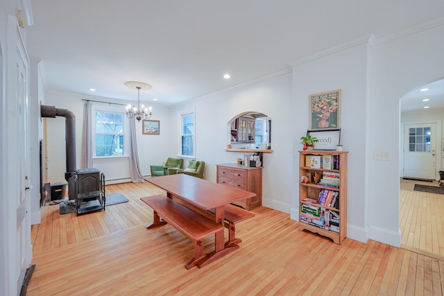 dining room featuring ornamental molding, recessed lighting, light wood-style flooring, a wood stove, and arched walkways