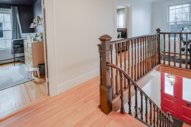 staircase featuring wood finished floors, baseboards, and baseboard heating