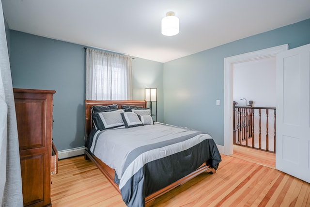 bedroom with baseboard heating, baseboards, and wood finished floors