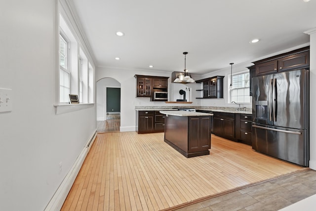 kitchen with ornamental molding, dark brown cabinets, arched walkways, light wood finished floors, and stainless steel appliances