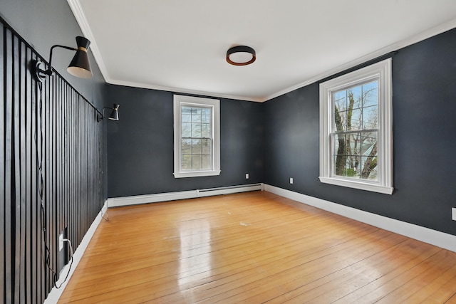 unfurnished room featuring ornamental molding, a baseboard heating unit, hardwood / wood-style floors, and a wealth of natural light