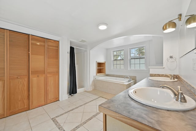 full bath featuring a garden tub, a sink, tile patterned floors, and double vanity