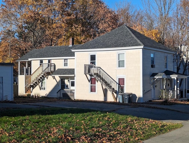 view of front of home with concrete block siding, roof with shingles, and stairs