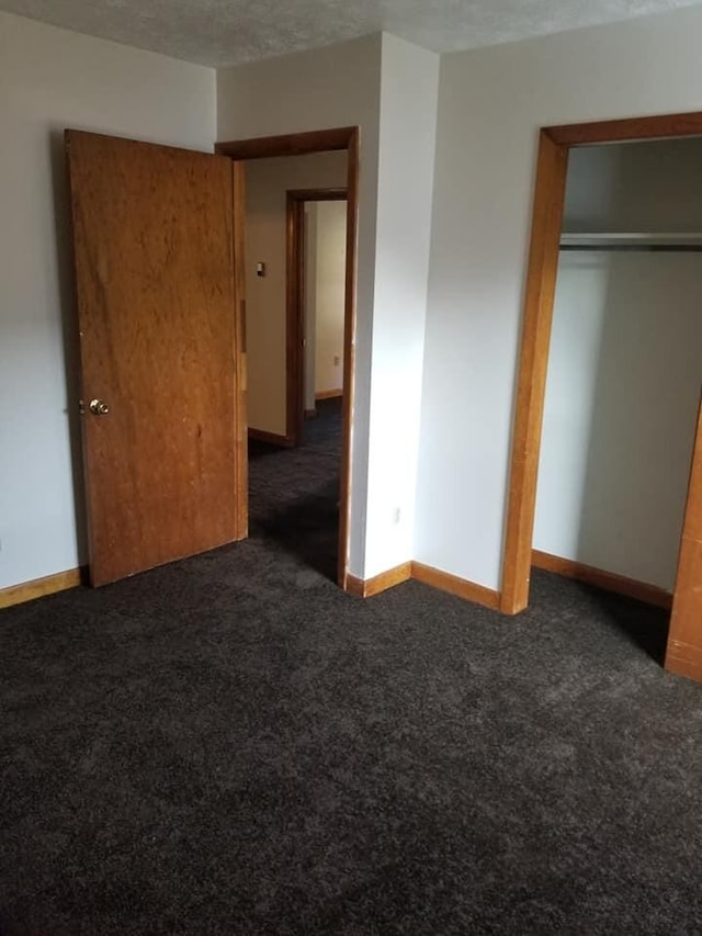 unfurnished bedroom with a closet, a textured ceiling, baseboards, and carpet floors