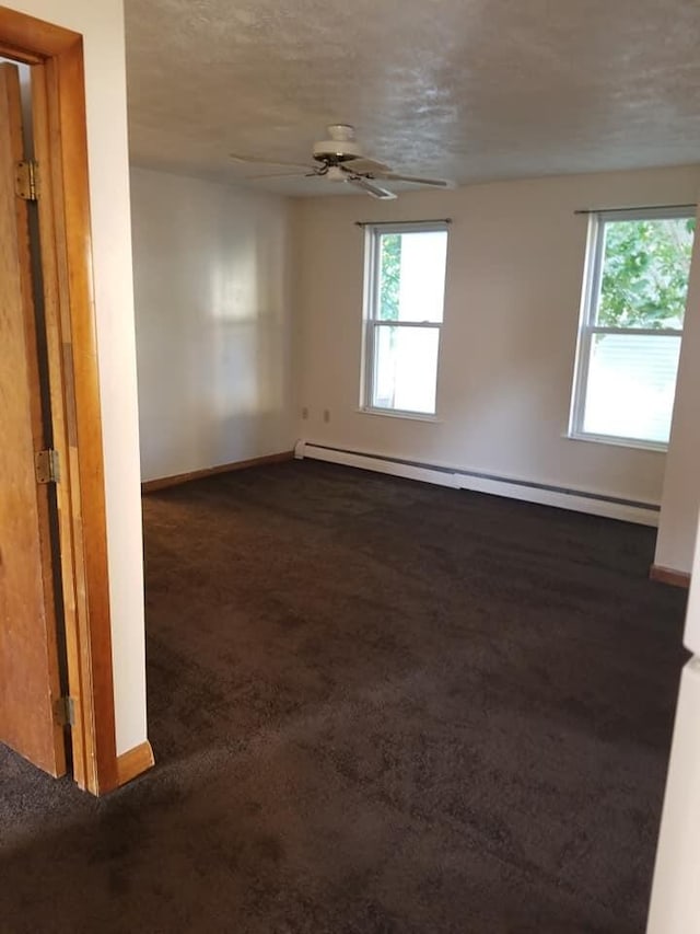 empty room featuring a baseboard radiator, baseboards, dark colored carpet, and ceiling fan