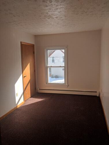 unfurnished room with dark carpet, a textured ceiling, a baseboard heating unit, and baseboards