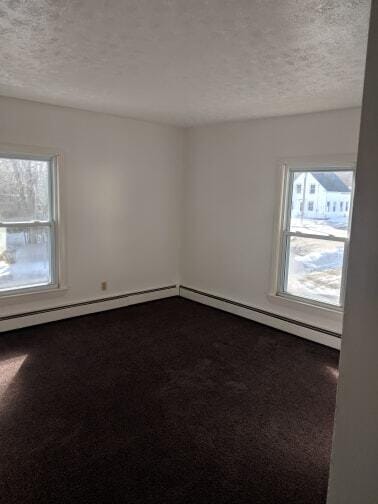 unfurnished room featuring dark carpet and a textured ceiling