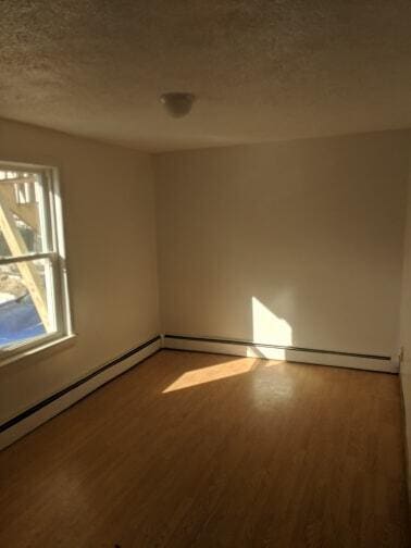 unfurnished room with a textured ceiling and wood finished floors