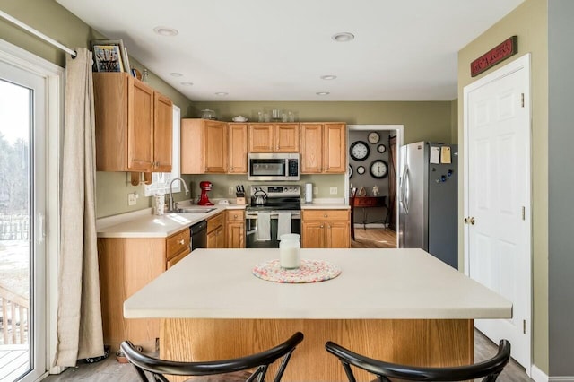 kitchen featuring a breakfast bar area, recessed lighting, a sink, light countertops, and appliances with stainless steel finishes