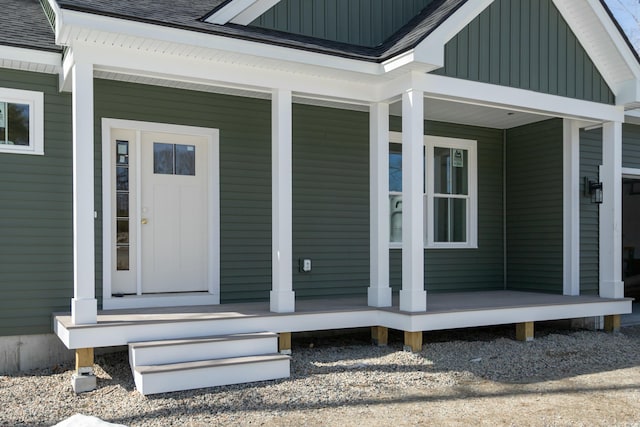 doorway to property with board and batten siding, roof with shingles, and covered porch