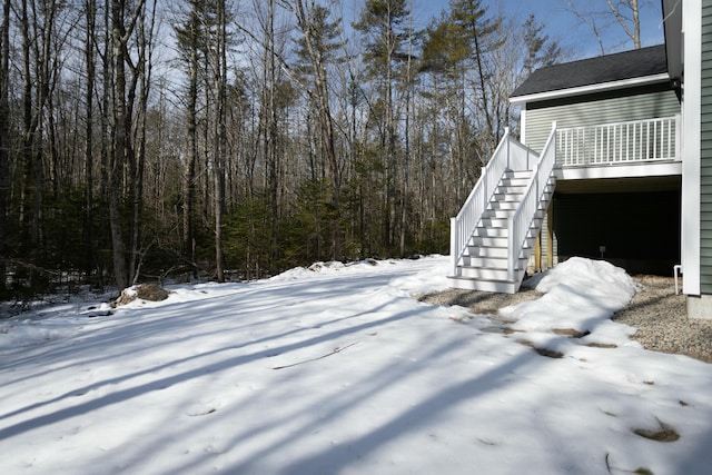 snowy yard featuring stairs and a view of trees