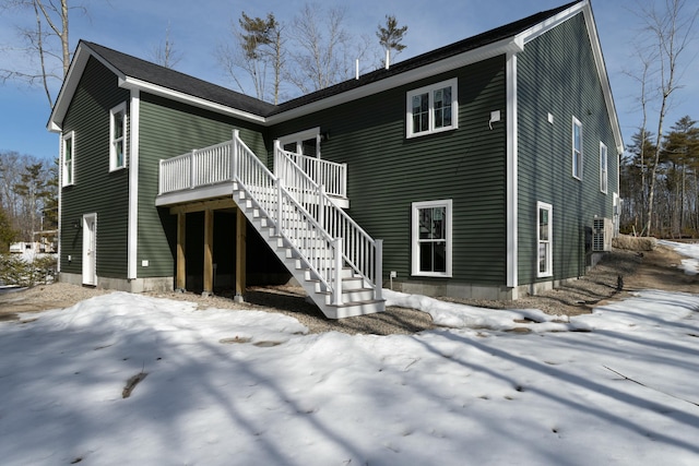 snow covered back of property featuring stairway and a wooden deck