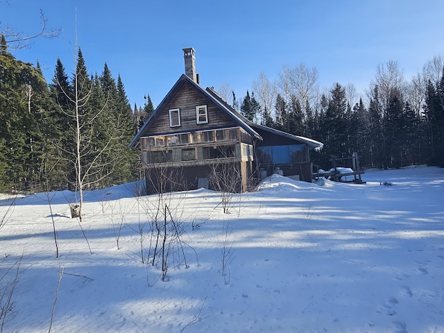 snow covered back of property featuring a carport