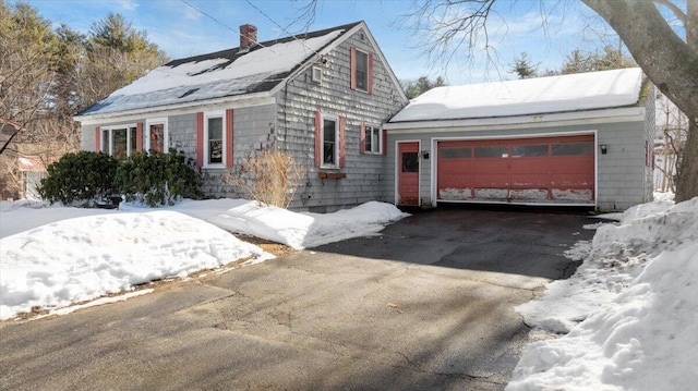 view of front of house with aphalt driveway, an attached garage, and a chimney