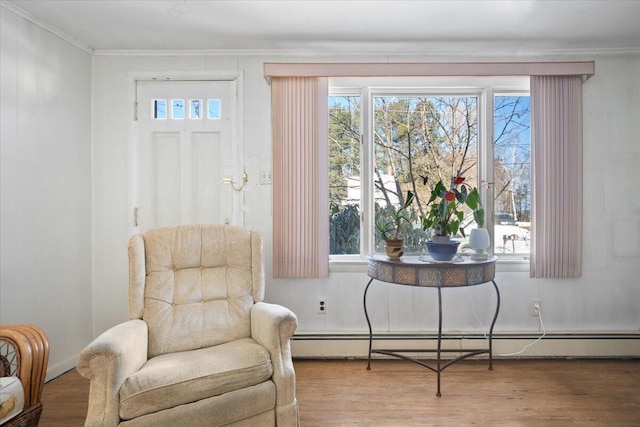 living area with baseboard heating, ornamental molding, and wood finished floors