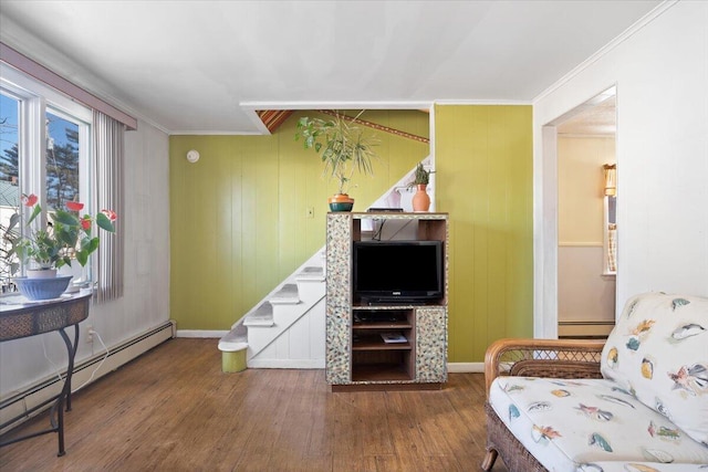 living room with crown molding, stairs, a baseboard heating unit, and wood finished floors