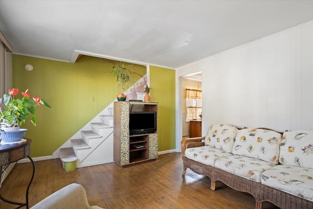 living area featuring stairway, ornamental molding, baseboards, and wood finished floors