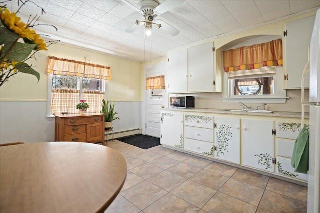 kitchen with light countertops, a wealth of natural light, baseboard heating, and a sink