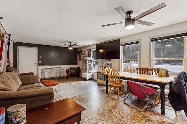 dining room featuring a wood stove, a textured ceiling, and a ceiling fan